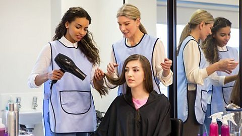 Two student hair dressers learning how to blow dry hair. 