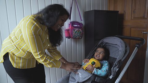 Mother putting her baby daughter into a pram 