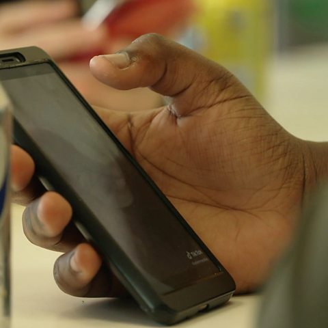 A close up of a hand holding a phone, watching an online video.