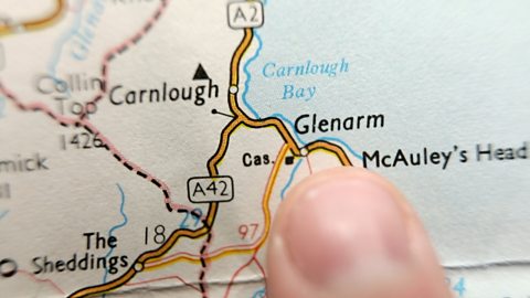 Close up photo of a finger pointing at a map showing the village of Glenarm in Northern Ireland