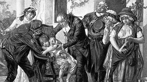 A drawing of Edward Jenner giving a small boy a vaccination in the arm while a crowd watches