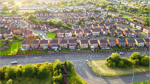 Aerial view of a suburban housing estate and roads that are surrounded by trees.