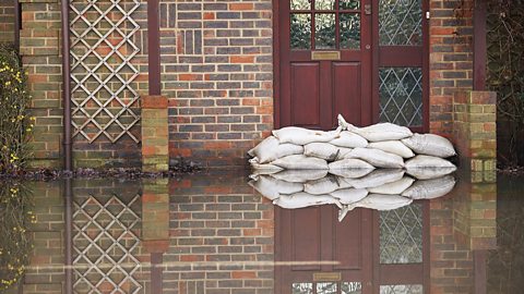 Sandbags sitting outside the front door of a house during a flood.