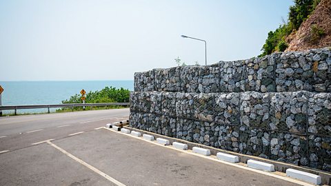 Gambions, rocks in metal cages, along a roadside by the sea