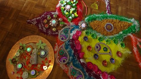 A colourful rangoli pattern made from powder, flowers and candles 