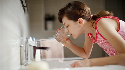 A girl rinsing her mouth with water at the sink