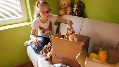 A girl putting her toys into a donation box