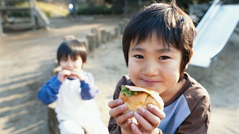 Boys eating hamburgers outdoors