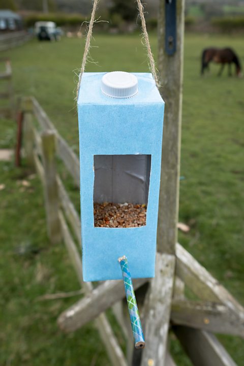 An old milk carton which has been recycled and modified as a bird feeder.