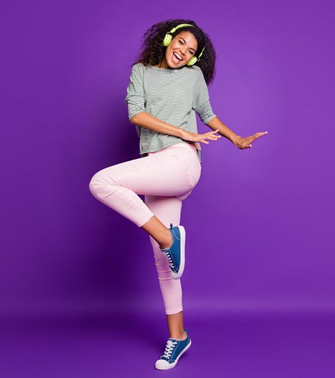 woman dances wearing pink jeans and striped top