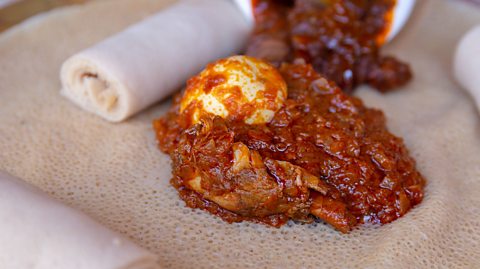 Injera served with Chicken and egg Doro Wat. Injera is a sourdough flatbread made from teff flour. It is the national dish of Ethiopia.