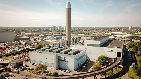 The London Energy EcoPark waste-to-energy power station. A number of tall buildings and one large chimney.