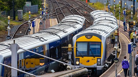 Two yellow, blue and silver trains approaching a station platform