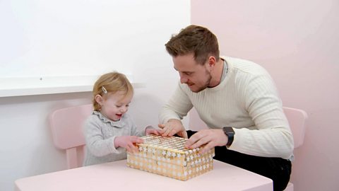 Father and daughter playing with wrapping paper