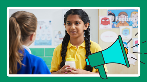 A girl talking to another girl in a classroom with a cartoon loudspeaker overlaid