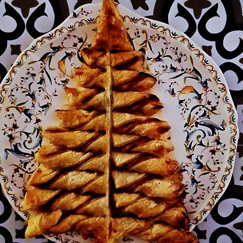 A picture of a Christmas tree made of puff pastry on a plate.