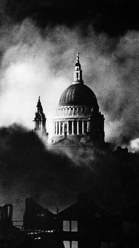 A black and white photograph of St Paul's Cathedral during the Blitz, with smoke surrounding it.