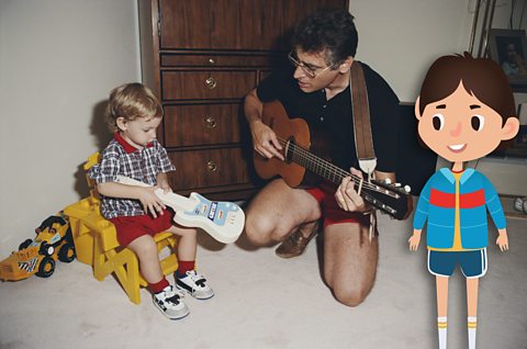 Father and son playing a guitar and electronic toy guitar.