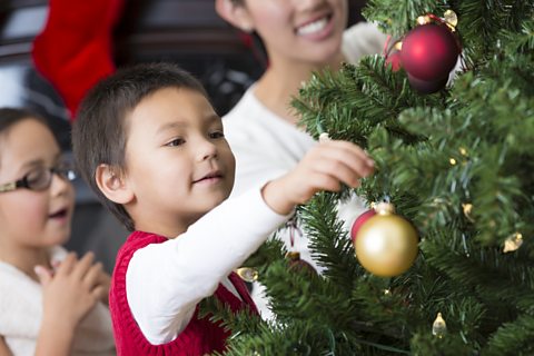 children decorating a Christmas tree with baubles 