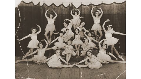 A black and white photograph of a group of children at a ballet class, all wearing tutus.