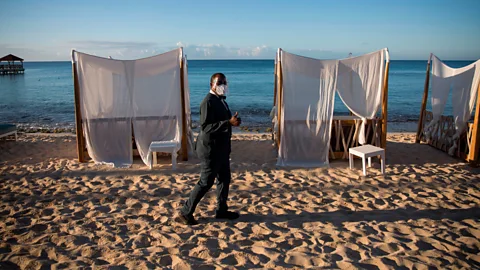 Erika Santelices/AFP/Getty Images Masked worker in deserted beach resort (Credit: Erika Santelices/AFP/Getty Images)