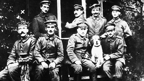 A black and white photograph of Adolf Hitler (who is sitting on the far left of the picture, in the front row) with some of his army colleagues during World War One.