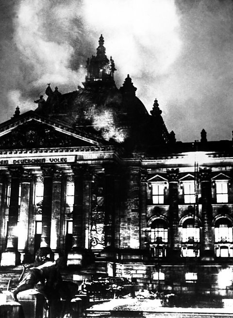A black and white photograph of the Reichstag building on fire in 1933.
