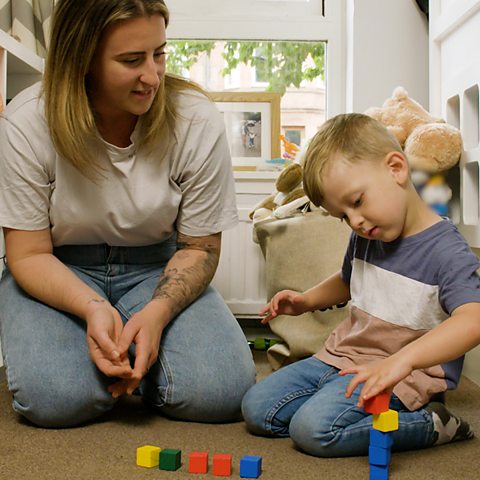 Toddler playing with building blocks with his mum.