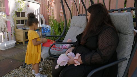 A mum and her daughter playing with dolls.