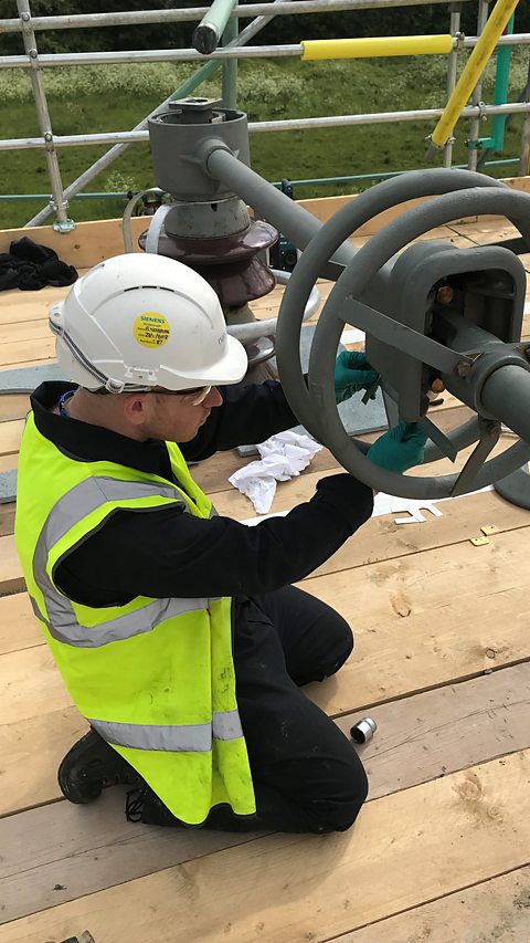 Adam is kneeling and checking some piece of equipment.