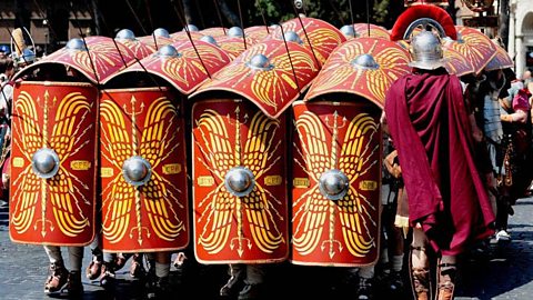 Roman reenactors charge with their bright yellow and red shields. 