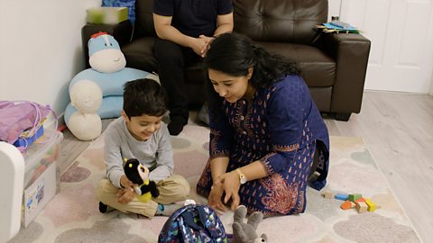 A mum and her son play on the floor with toys.