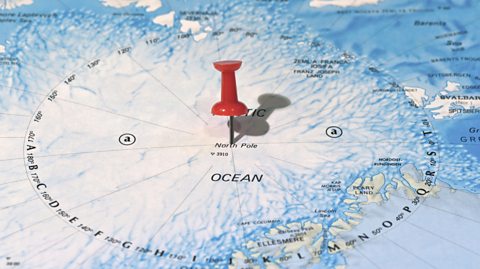 A red pin marks the spot of the geographic North Pole on a coloured map