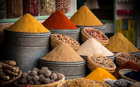 Heaps of yellow, brown and red spices at a market. 