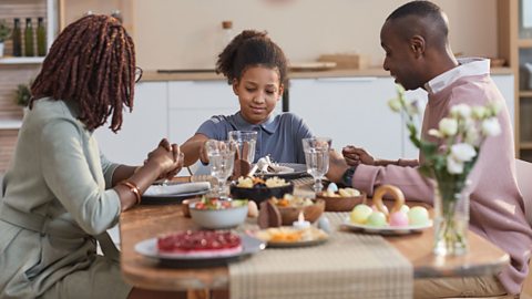 A teenager sits at the dinner table with her parents and the three of them eat