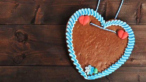 Lebkuchen in heart shape with blue icing around the side and read hearts at the top 
