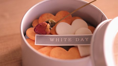 A box of heart shaped cookies with white day label across the top