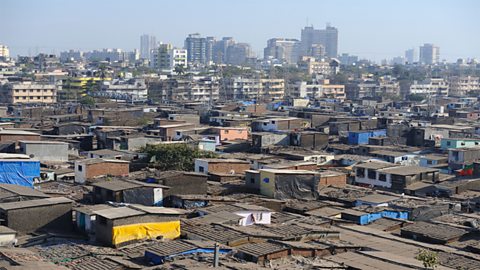 Lots of houses in Dharavi, an informal settlement, with taller buildings in the background.