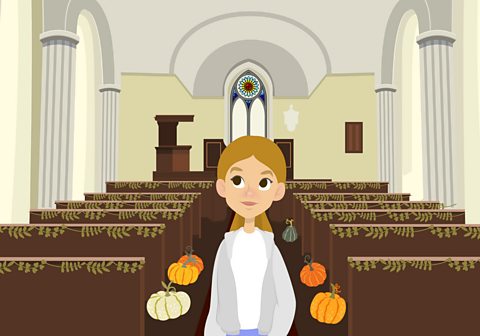 Hannah stood in the church which is decorated for Harvest Festival.