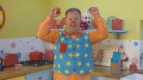 Mr Tumble from the CBeebies show something special is cheering in his kitchen. He's holding 2 new juggling balls.