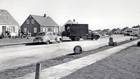 A group of people emptying a removal van outside a bungalow house