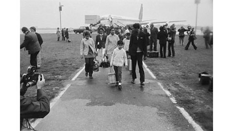 A black and white photograph of Ugandan Asians arriving at Stansted Airport.