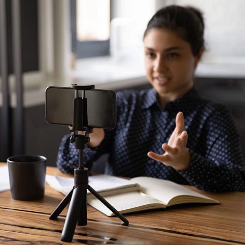 A young person recording a video of themselves on their phone.