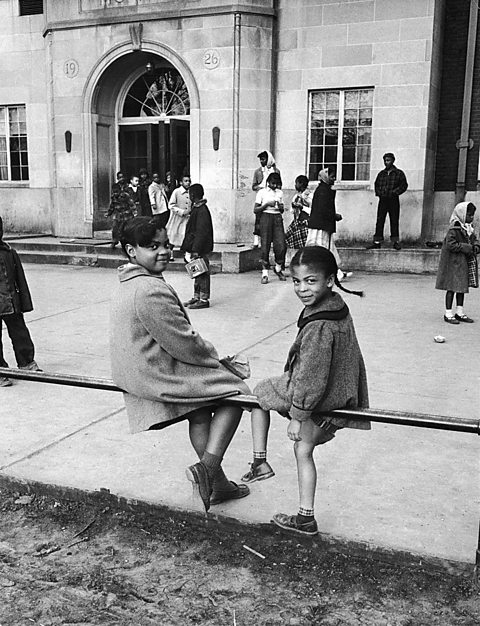 Sisters Linda and Terry Lynn Brown sit on a fence outside of their school, the racially segregated Monroe Elementary School, Topeka, Kansas, March 1953.