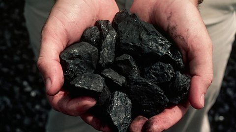 Carbon or coal in someone's hands