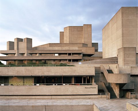 A photo of the exterior of the National Theatre. The building has multiple layers and towers, all of which are made from concrete and give the appearance of different blocks stack on each other.