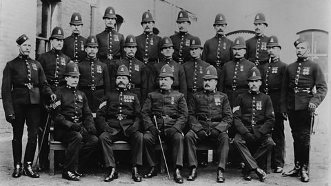 Black and white photograph of twenty policemen posing in rows and wearing police uniform