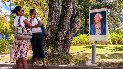 Hemis/Alamy Stock Photo Women stop for a chat in front of an image of Lieutenant Charles Routier de Romainville, founder of the city of Victoria (Credit: Hemis/Alamy Stock Photo)
