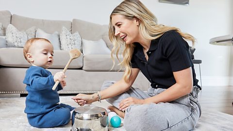 Dani Dyer and Santiago playing with a wooden spoon and pan.