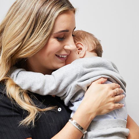 Dani Dyer hugs her baby son Santiago on a white background